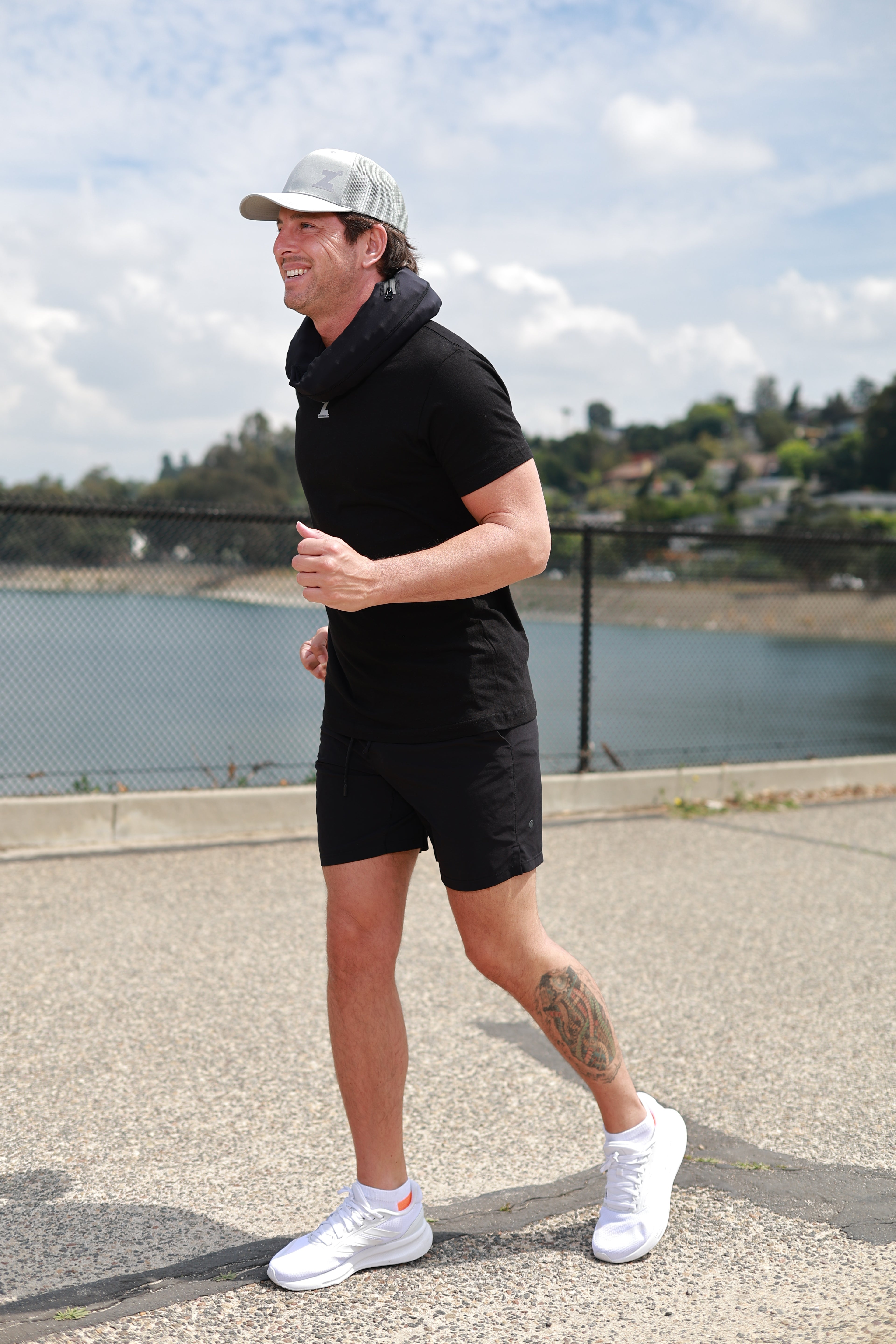 Man exercising outdoors on a paved path with a scenic background with the HERO around his neck